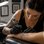 Fine line tattoo artist creating delicate minimalist tattoo design